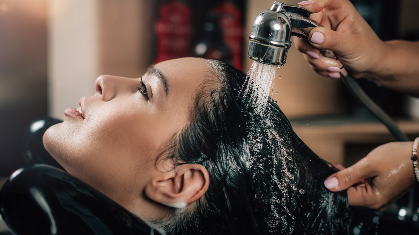 A woman having her hair extensions washed in the salon